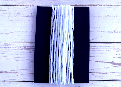 The yarn should be wrapped 25 times around a cardstock paper. Ensure that the yarn is snug without being so tight that the card begins to bend.  Then cut the yarn and set it aside.  Note: When using scissors, adult supervision is advised.